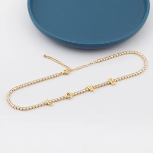 Detail showing gold LOVE letter pendant and zircon stones on a gold-plated link chain