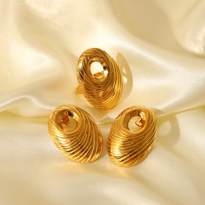 Close-up of gold vintage spiral texture jewelry set with hollow oval rings and earrings