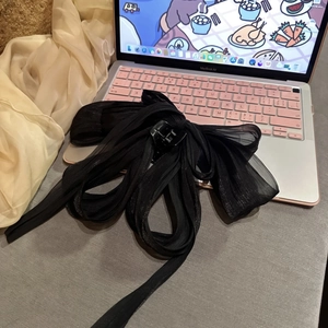 Close-up of a large black chiffon bow hair claw clip placed on a laptop keyboard