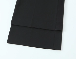Vue détaillée de la texture du tissu tissé noir et de l'ourlet du pantalon de costume