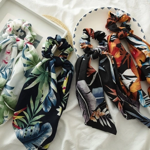 Detail of satin scrunchies with long ribbons featuring tropical floral and leaf patterns