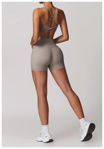 Dettaglio del set yoga tortora con reggiseno sportivo incrociato e pantaloncini a vita alta