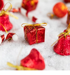 Macro shot of red Christmas tree ornaments with festive gift boxes and golden bells