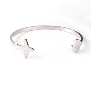 Detail of silver travel bracelet featuring airplane charm and world map engraved pendant