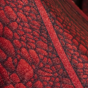 Close-up of red non-woven dragon wing fabric with metallic glitter and cell-like texture