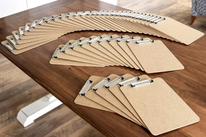 Massive set of brown fiberboard A4 clipboards with silver metal clamps on a wooden desk