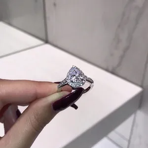 Elegant silver pear-cut halo engagement ring with sparkling zircon stones on a female hand
