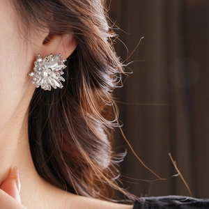 Close-up detail of silver floral stud earrings featuring sparkling rhinestones on model