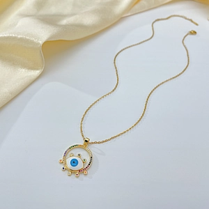 Macro shot of evil eye pendant with blue enamel and colorful zircons on gold chain