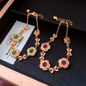 Detailed macro view of 24K gold-plated flower links with red and green gemstones