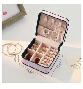 Macro detail of compact pink leather jewelry box showing necklace hooks and ring slots