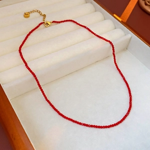 Détail d'un collier de perles facettées rouges avec fermoir doré sur un présentoir de luxe