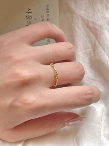 Close-up of minimalist gold bow ring worn on finger with aesthetic book background