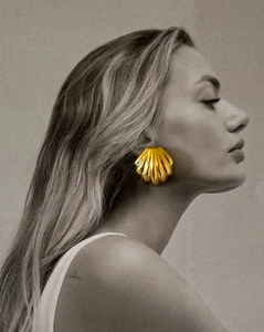 Detail of 18K gold stainless steel seashell stud earring on woman's earlobe