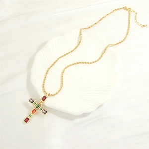 Collana a croce placcata in oro con zirconi colorati su un vassoio a conchiglia bianca
