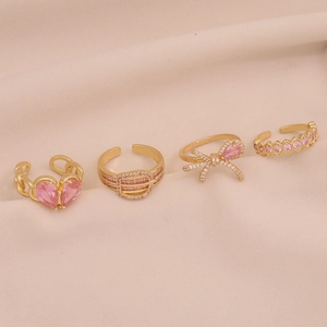 Ensemble de bagues dorées avec zircons roses cœur et nœud sur velours rose