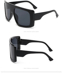 Detail view showing oversized thick black square frame and grey lenses of these sunglasses
