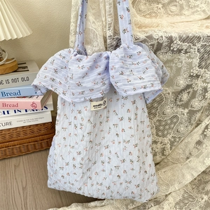Detail view of floral canvas tote bag featuring light blue patterns and ruffled handles