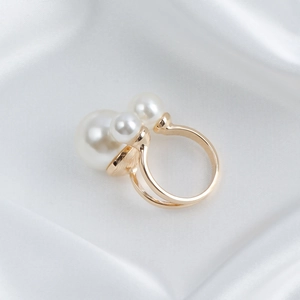 Golden double-layer open ring with three white pearls on elegant white silk background