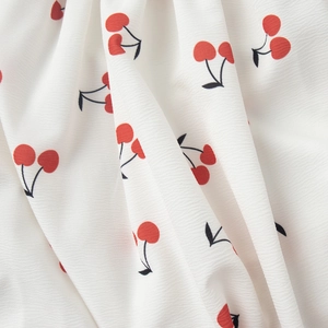Macro detail of white chiffon fabric with red cherry print and fine horizontal texture