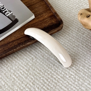Détail de la pince à cheveux en acétate crème brillant sur bois et tissu tricoté