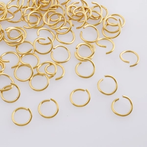 Macro shot of bulk golden open jump rings for DIY jewelry making on white background