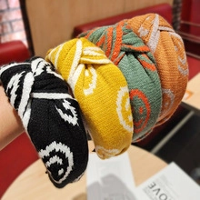 Nahaufnahme von vier Strick-Knoten-Stirnbändern mit Smiley-Muster in Schwarz, Gelb, Grün, Orange