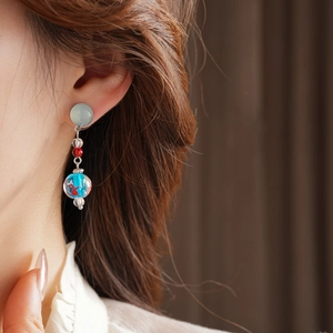 Detail of a starfish earring with glass beads and a blue globe on a silver needle chain