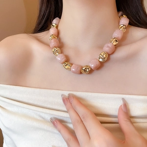Detail of pink marble resin beads and irregular golden metal beads on a bracelet