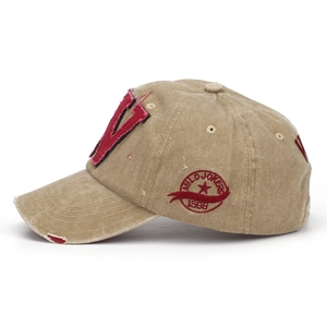 Detail of washed khaki baseball cap featuring vintage embroidery and distressed brim