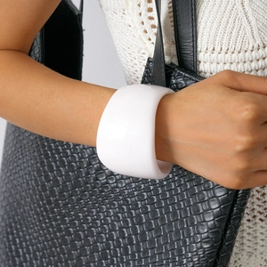 Close-up of white resin wide bangle bracelet with glossy finish on a woman wrist