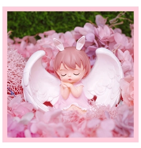 Close-up of a sleeping pink-haired angel girl resin ornament among hydrangea petals