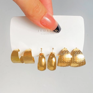 Detail of three pairs of gold geometric earrings with brushed and honeycomb textures