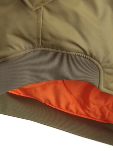Détail du blouson bomber vert olive avec doublure orange et texture de l'ourlet