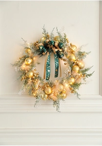 Detail of Christmas wreath with gold baubles, pine needles, and warm LED lights
