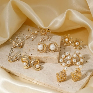 Elegant gold pearl stud earring set with floral, bow and geometric shapes on silk