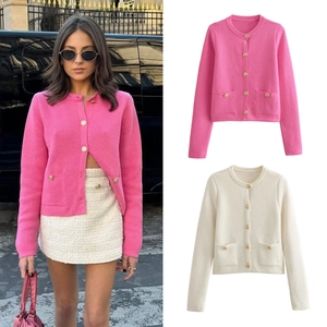 Close-up of knit cardigans in pink and off-white with elegant gold buttons