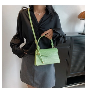 Detail showing mint green pleated handbag texture and woven knot handle on fashion bag