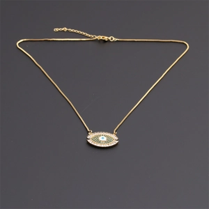 Macro detail of gold-plated Evil Eye necklace featuring green and white cubic zirconia