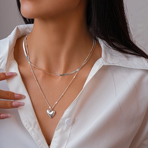 Close-up of double-layered silver heart necklace with snake chain and heart pendant