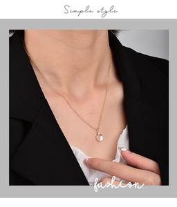 Close-up of minimalist gold chain necklace with iridescent round opal pendant on a model