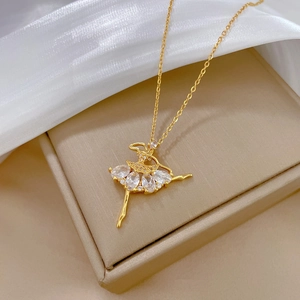 Elegant gold ballerina pendant necklace with sparkling crystals on white silk background