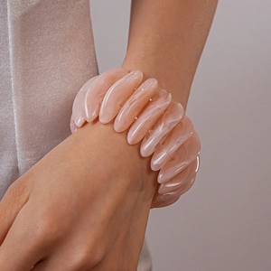 Detail shot of wide pink marble resin bracelet with smooth oval segments on wrist