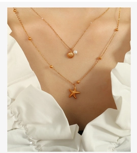 Close-up of a double-layered gold starfish and shell necklace on a female model