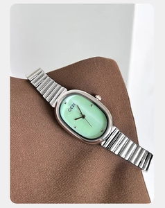 Detail view of oval mint green watch dial with silver stainless steel stretch band