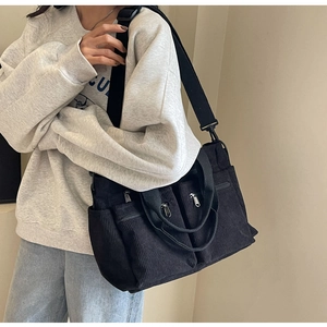 Detail of black corduroy crossbody bag showing textured fabric and adjustable straps