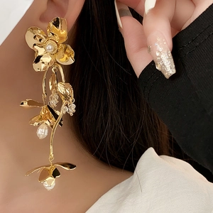 Detail of elegant gold layered flower earrings with pearls and matte finish shown on model