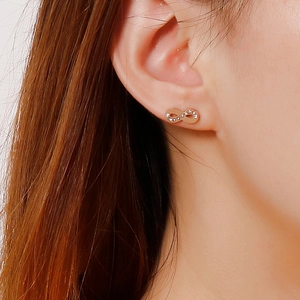 Macro shot of rose gold infinity stud earring with crystals on model's ear