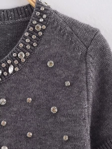 Detailed view of dark grey knit top featuring sparkly rhinestone collar and studs