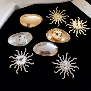 Detailed view of metal sunburst and pebble brooches in gold and silver finishes